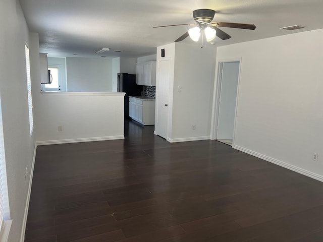 empty room featuring baseboards, visible vents, ceiling fan, and dark wood-type flooring