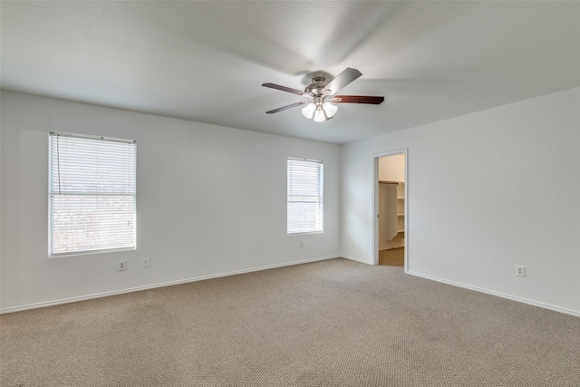 unfurnished room with a ceiling fan, light colored carpet, and baseboards