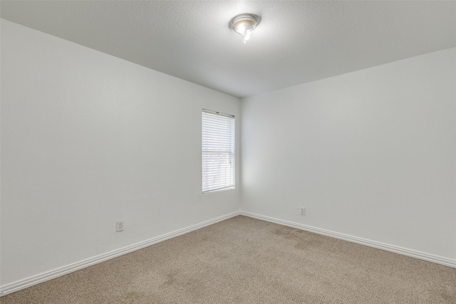 carpeted empty room with a textured ceiling and baseboards