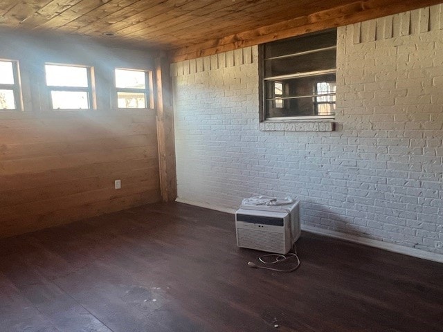 empty room with brick wall, a wall mounted AC, dark hardwood / wood-style flooring, and wood ceiling