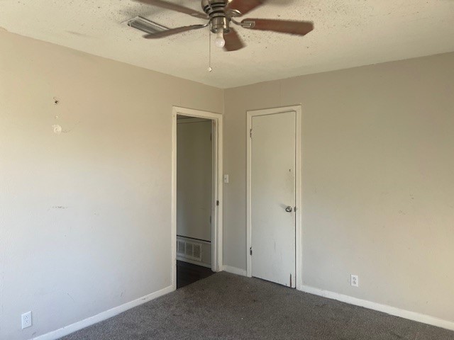 spare room featuring ceiling fan, dark colored carpet, and a textured ceiling