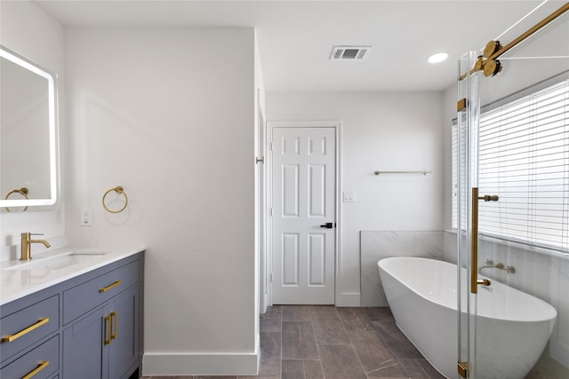 bathroom featuring tile patterned flooring, vanity, and a washtub