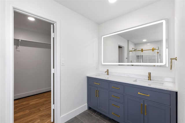 bathroom with a shower with door, vanity, and wood-type flooring