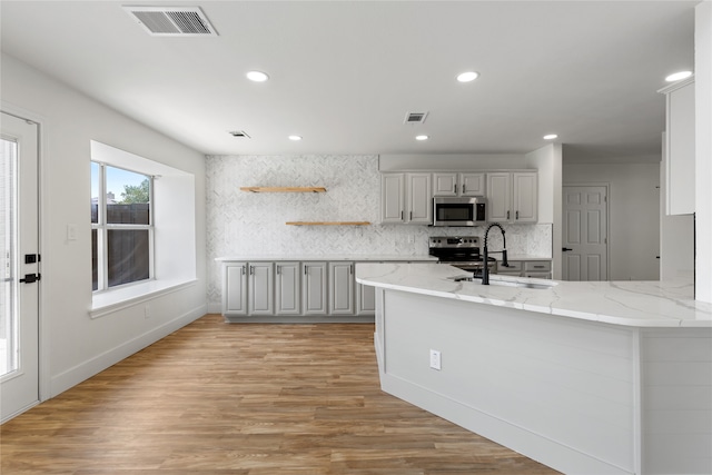 kitchen featuring light hardwood / wood-style flooring, stainless steel appliances, sink, and kitchen peninsula