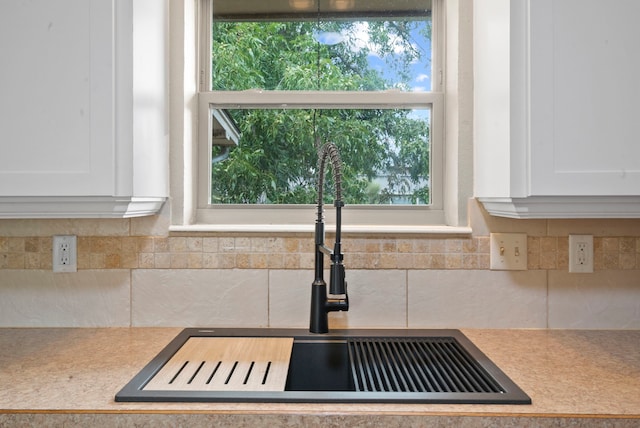 kitchen with tasteful backsplash, white cabinetry, and sink