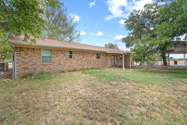 back of property with a yard and central AC