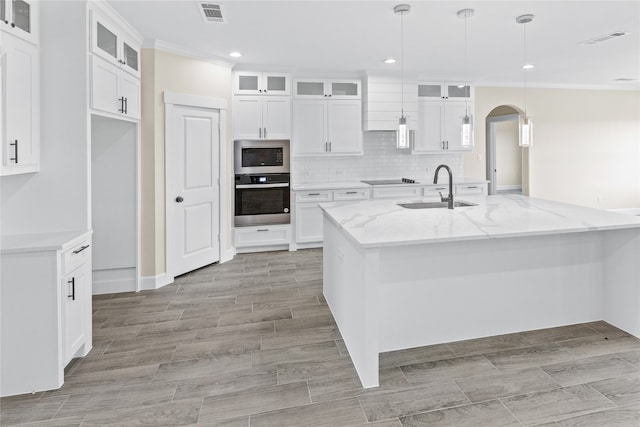 kitchen featuring stainless steel appliances, light stone counters, sink, hanging light fixtures, and white cabinets