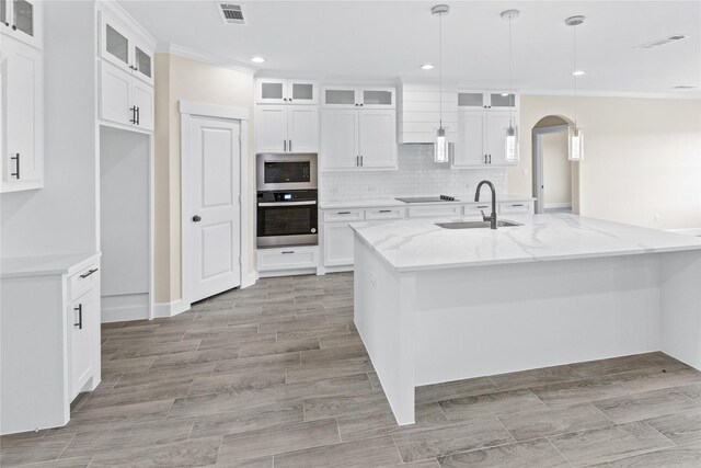 kitchen with a sink, stainless steel appliances, arched walkways, and visible vents