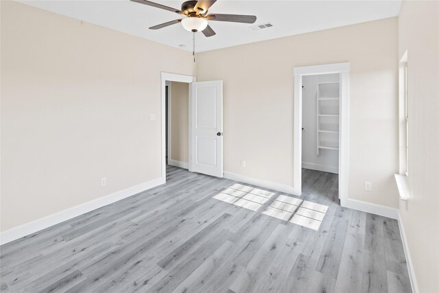 unfurnished bedroom with baseboards, visible vents, a spacious closet, a closet, and light wood-type flooring