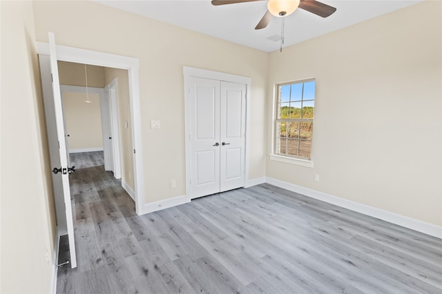 unfurnished bedroom featuring ceiling fan, a closet, and light wood-type flooring