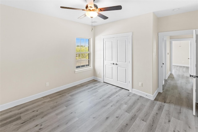 unfurnished bedroom with a closet, light wood-style flooring, baseboards, and ceiling fan