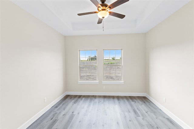 spare room featuring a tray ceiling, light hardwood / wood-style flooring, and ceiling fan