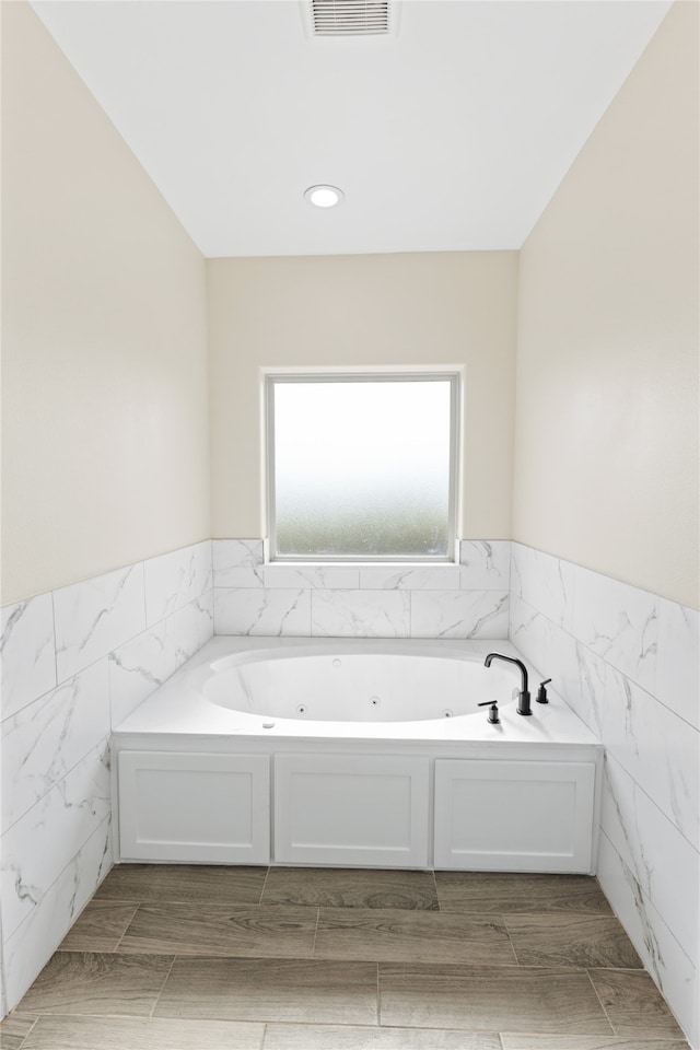 bathroom with tile walls and a bathtub