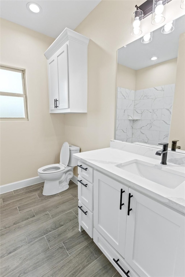 bathroom featuring vanity, baseboards, wood finish floors, recessed lighting, and toilet