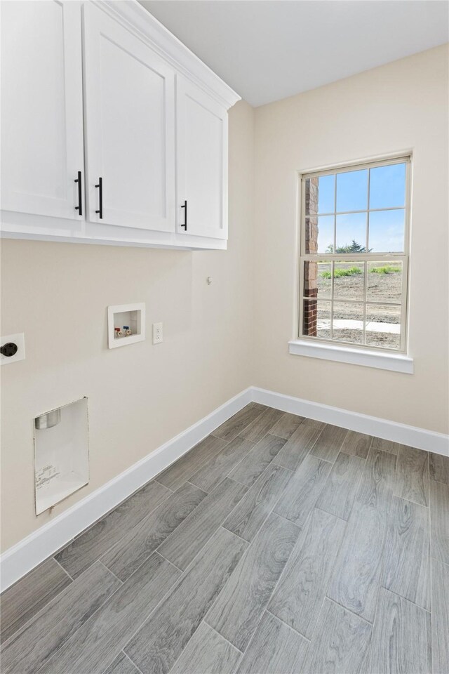 clothes washing area featuring wood finished floors, cabinet space, baseboards, hookup for an electric dryer, and hookup for a washing machine