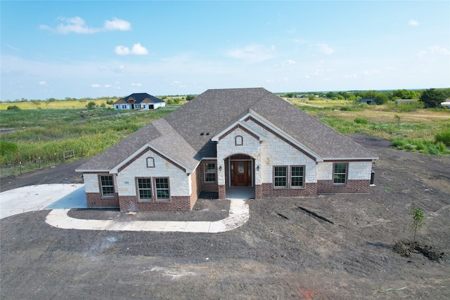 french provincial home with stone siding, brick siding, and roof with shingles