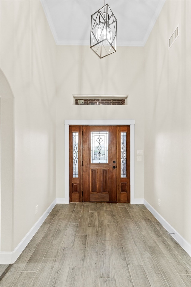 entryway featuring light wood-type flooring, a chandelier, and ornamental molding