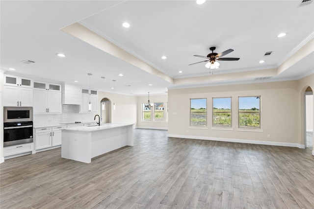 kitchen with a tray ceiling, open floor plan, and stainless steel appliances