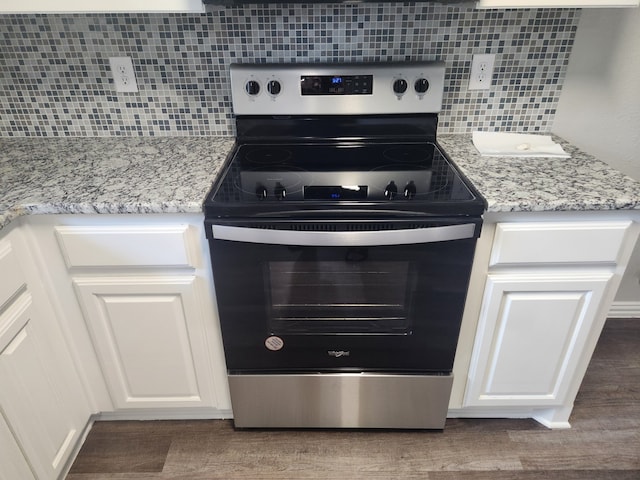 kitchen with light stone counters, stainless steel electric stove, decorative backsplash, and white cabinetry