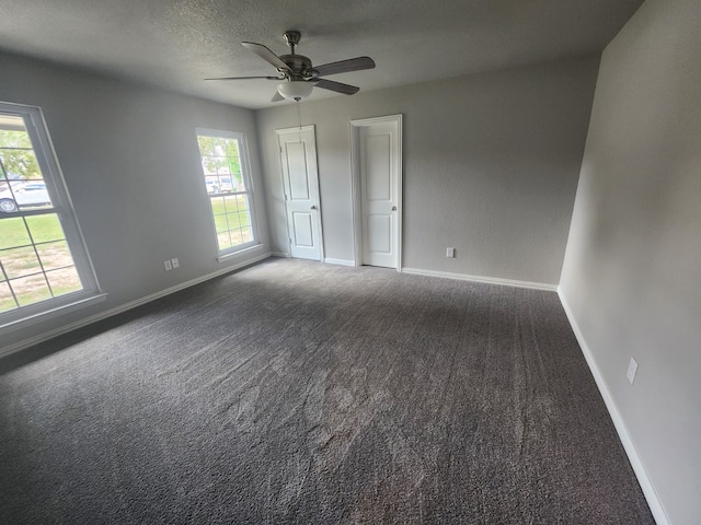 unfurnished bedroom with a textured ceiling, carpet flooring, ceiling fan, and multiple windows