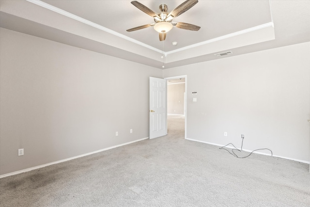 carpeted spare room with crown molding, a raised ceiling, and ceiling fan