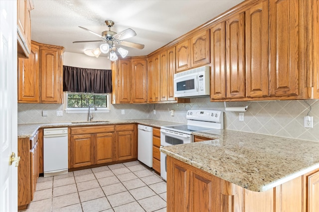 kitchen featuring white appliances, light stone counters, sink, kitchen peninsula, and ceiling fan