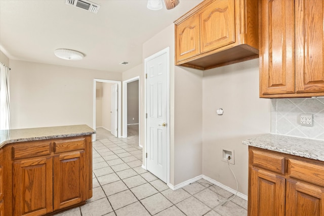 kitchen featuring tasteful backsplash, light stone counters, light tile patterned floors, and ceiling fan