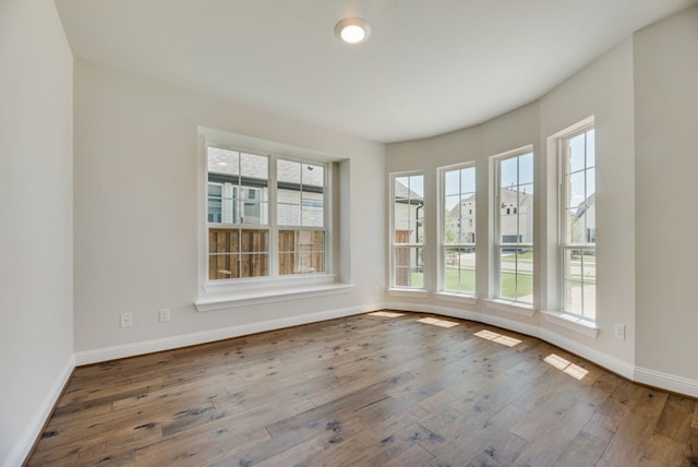 spare room featuring baseboards and hardwood / wood-style flooring