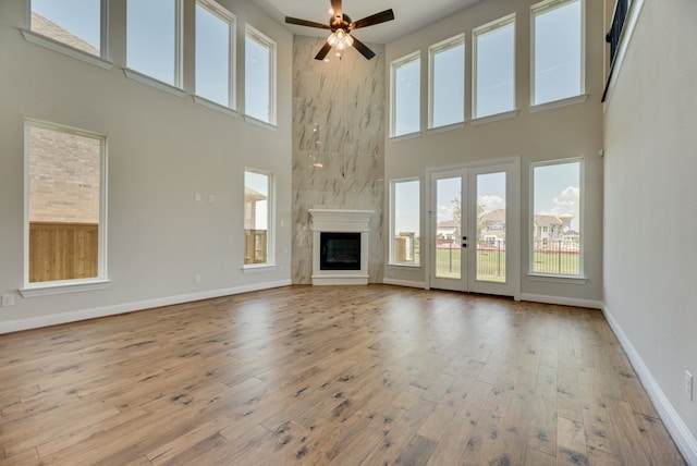 unfurnished living room featuring a wealth of natural light, a fireplace, ceiling fan, and a high ceiling