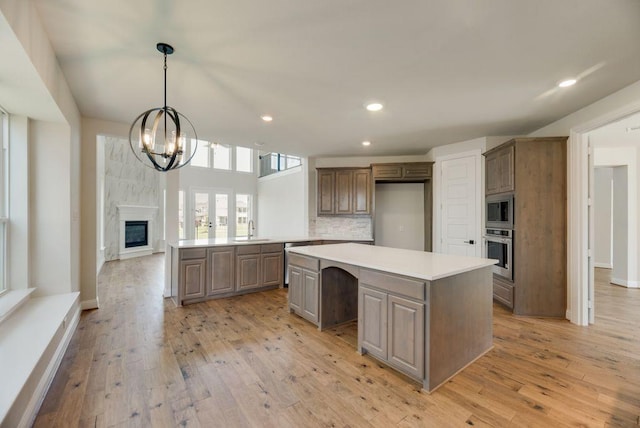 kitchen featuring appliances with stainless steel finishes, a center island, light wood-type flooring, and light countertops