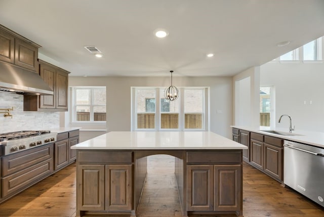 kitchen featuring a center island, sink, decorative backsplash, stainless steel appliances, and a chandelier