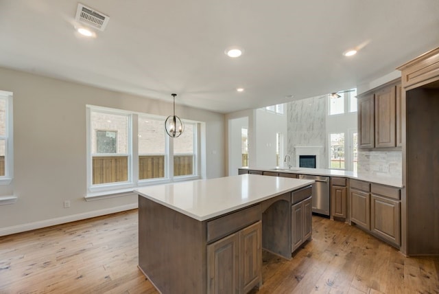 kitchen featuring visible vents, light countertops, a center island, dishwasher, and light wood finished floors