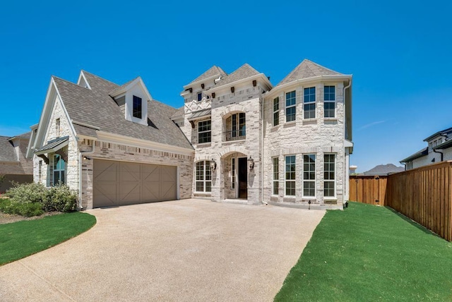 french country inspired facade with an attached garage, a front yard, fence, stone siding, and driveway