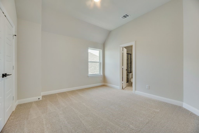 unfurnished bedroom with lofted ceiling, visible vents, light carpet, and baseboards