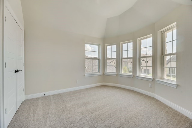 unfurnished room with light carpet, baseboards, a wealth of natural light, and lofted ceiling