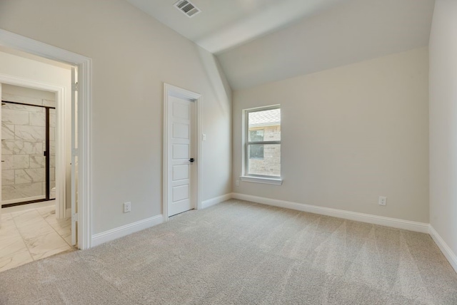 unfurnished bedroom featuring light colored carpet, connected bathroom, and vaulted ceiling