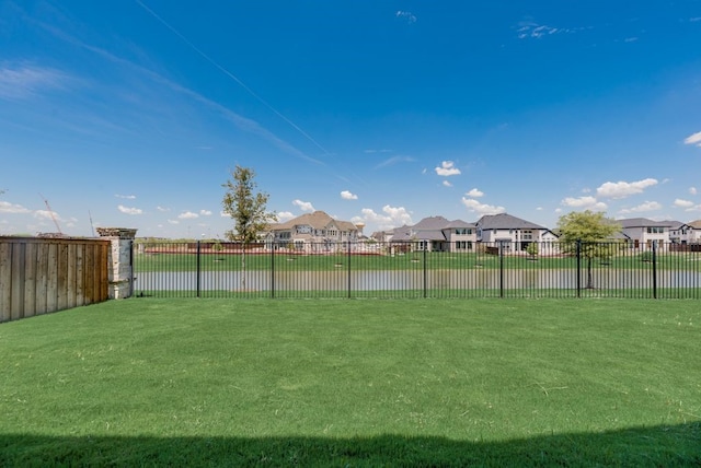 view of yard with a water view, a residential view, and fence