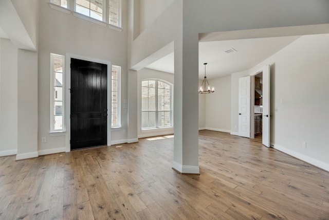 foyer entrance featuring a towering ceiling, a notable chandelier, baseboards, and hardwood / wood-style floors