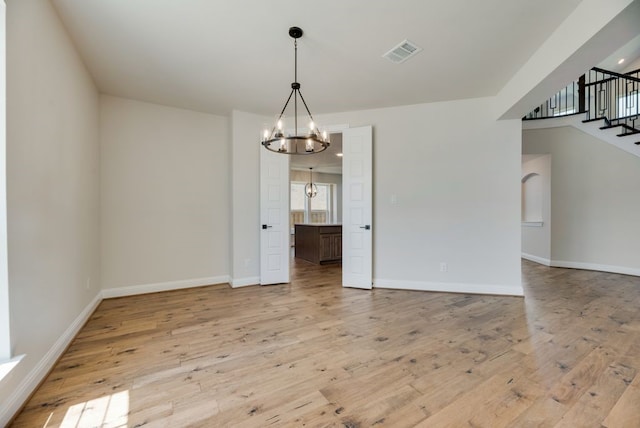 unfurnished dining area featuring a chandelier, baseboards, visible vents, and light wood-style floors