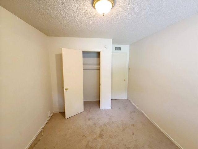 unfurnished bedroom featuring a closet, light carpet, and a textured ceiling