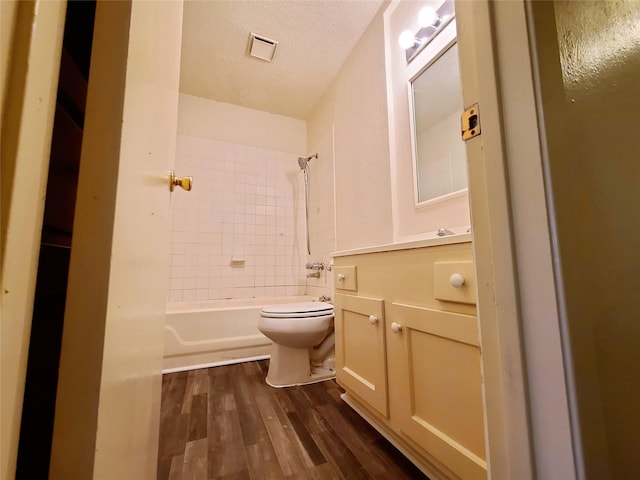 full bathroom featuring toilet, tiled shower / bath, vanity, a textured ceiling, and wood-type flooring