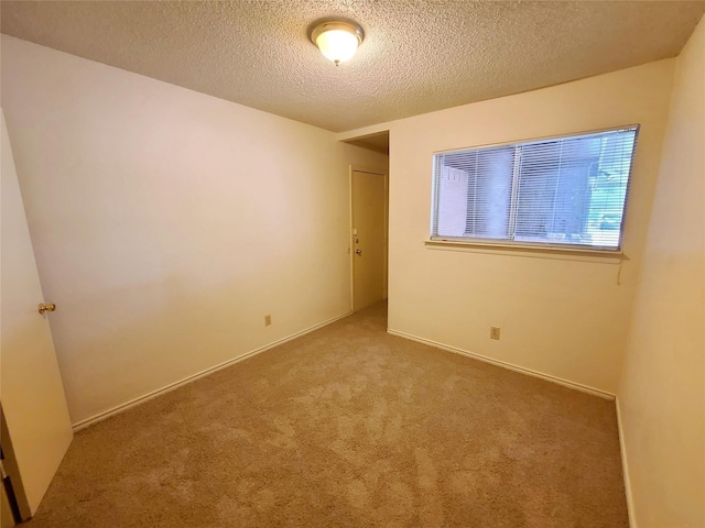 spare room with a textured ceiling and light carpet