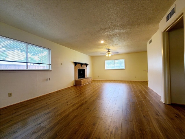 unfurnished living room with a fireplace, dark hardwood / wood-style flooring, ceiling fan, and a textured ceiling