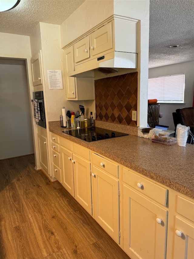 kitchen featuring a textured ceiling, black appliances, and dark hardwood / wood-style floors