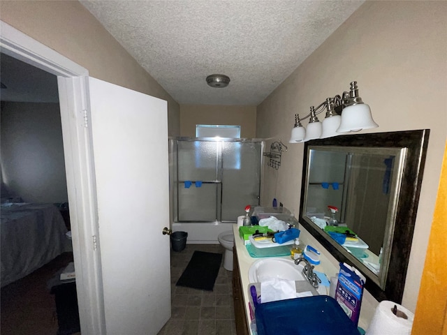 full bathroom with vanity, toilet, bath / shower combo with glass door, and a textured ceiling