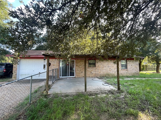 back of property featuring a garage, a patio area, and a lawn