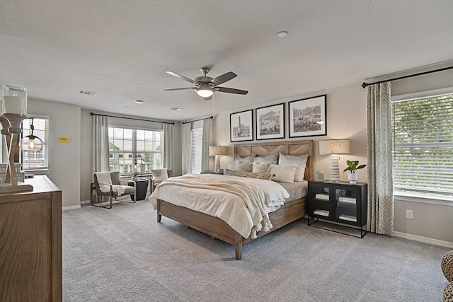 bedroom featuring ceiling fan, light carpet, and a textured ceiling