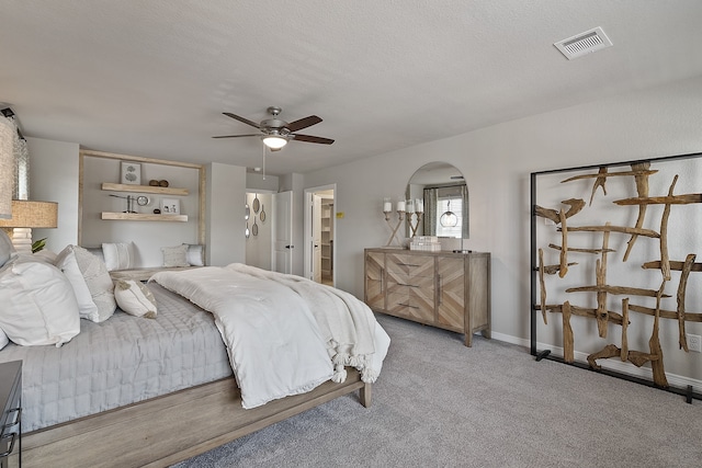 carpeted bedroom with a textured ceiling, ensuite bathroom, and ceiling fan