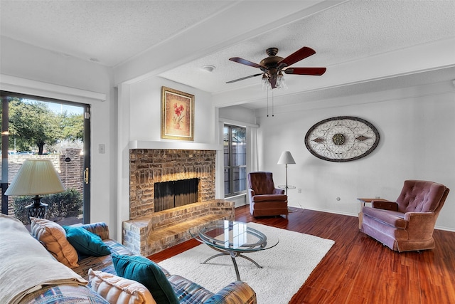 living room featuring dark hardwood / wood-style flooring, ceiling fan, a fireplace, and a textured ceiling