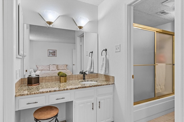 bathroom with vanity, tile patterned flooring, a textured ceiling, and combined bath / shower with glass door